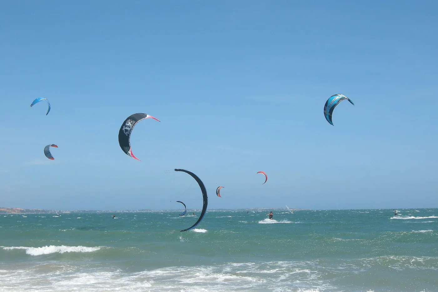 Kitesurfing kites over the water off Mui Ne beach with surf breaking in the foreground Kitesurfing kites over the water off Mui Ne beach with surf breaking in the foreground