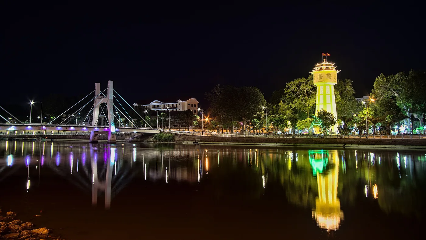 The floodlit water tower of Phan Thiet and the Le Hong Phong bridge reflected in the river at night The floodlit water tower of Phan Thiet and the Le Hong Phong bridge reflected in the river at night