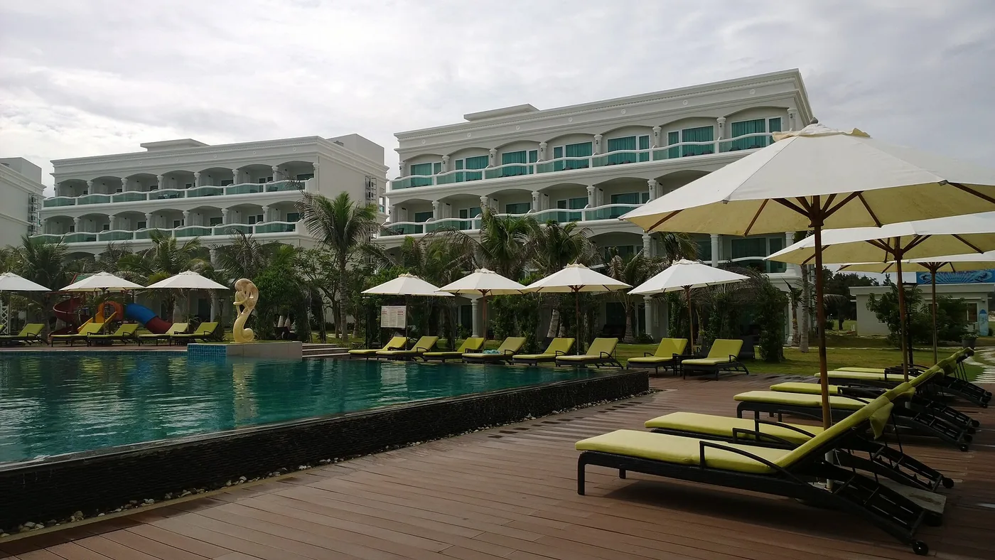 The pool, sun loungers and low resort blocks of a beachfront resort on the Mui Ne strip