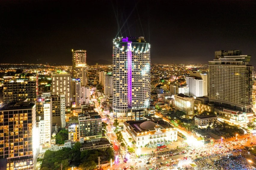 夜に灯りをともしたパノラマ・ニャチャンの円筒形の高層建物と周りの街