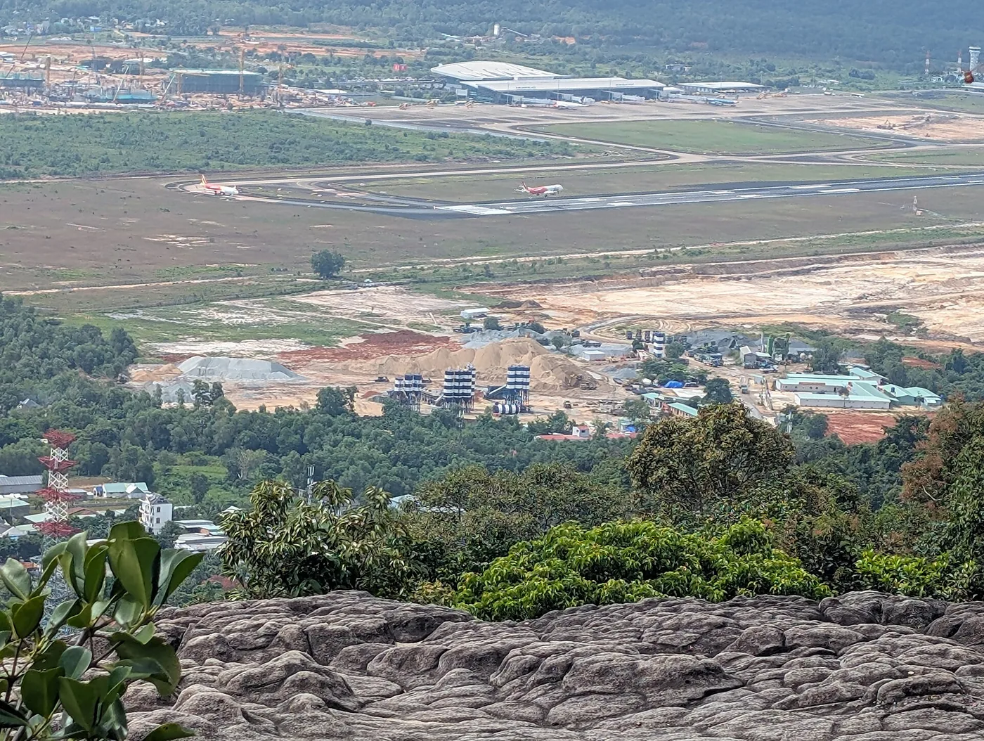 從山丘俯瞰富國島機場，跑道上停著兩架飛機，前方是有吊車和成堆沙子的大型工地