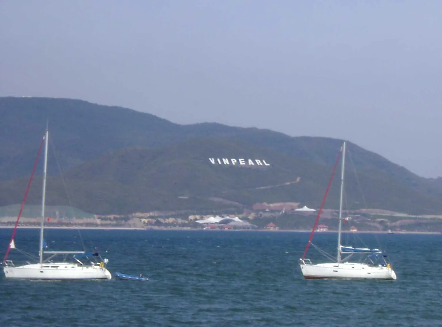 ニャチャン湾のヨット二艇と、その奥に VINPEARL の文字があるホンチェ島 ニャチャン湾のヨット二艇と、その奥に VINPEARL の文字があるホンチェ島