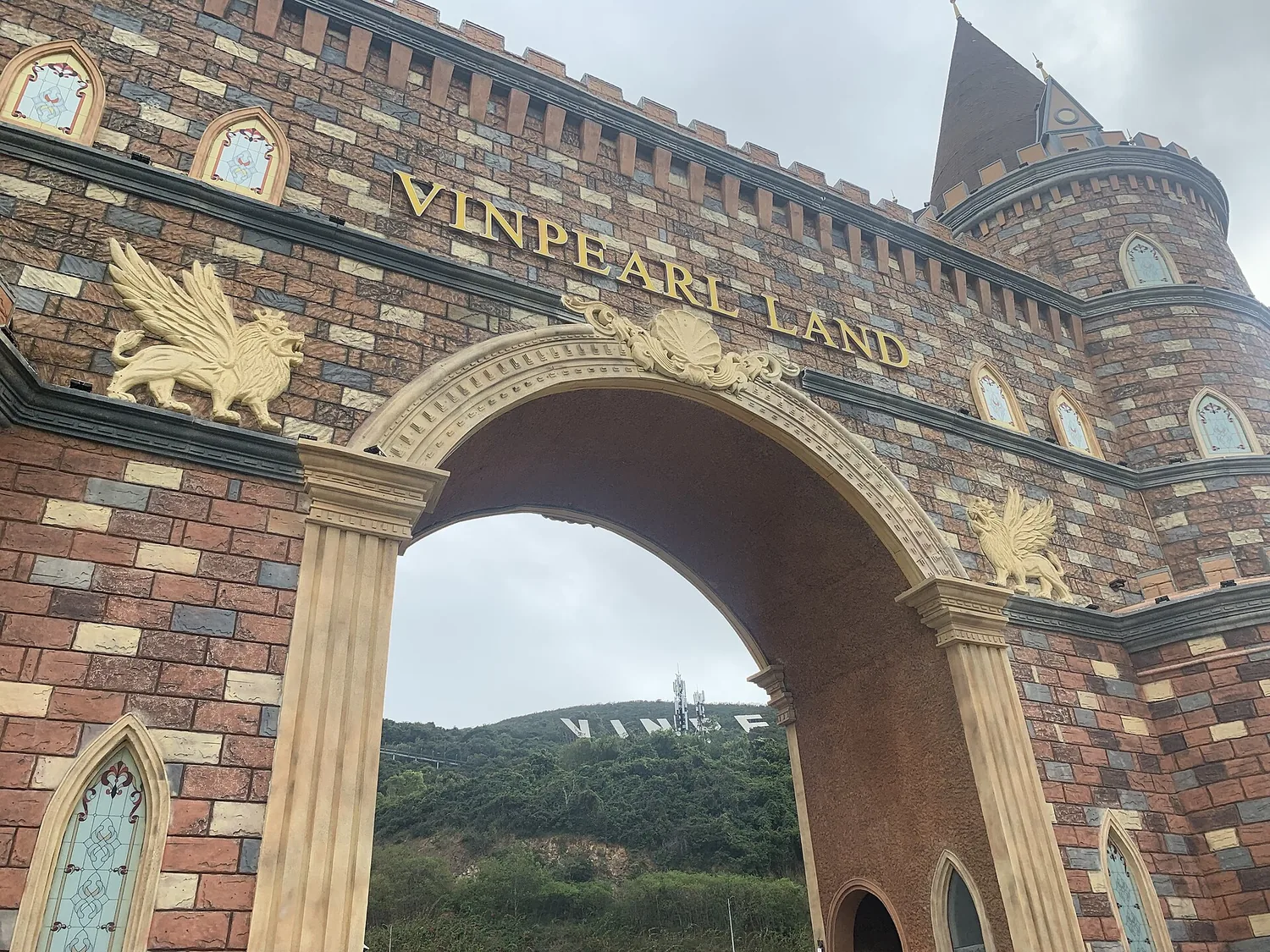 VINPEARL LAND と書かれた石のアーチと、その上の金色の装飾 VINPEARL LAND と書かれた石のアーチと、その上の金色の装飾
