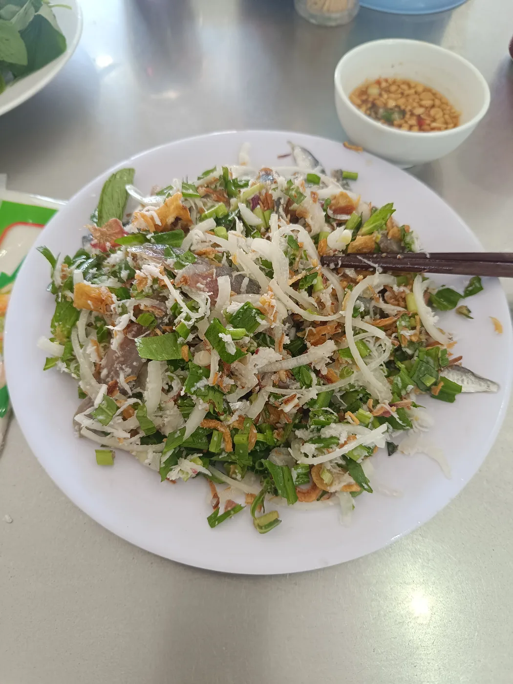 一盤涼拌生沙丁魚,上面有香草、洋蔥和花生 一盤涼拌生沙丁魚,上面有香草、洋蔥和花生